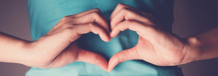 A person making a heart shape with their hands.
