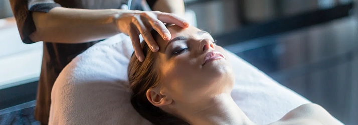 Chiropractic Torrance CA Reiki A person laying on a bed with a hand on their forehead.