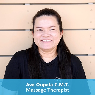 Massage Therapist Ava Oupala In Front Of Wooden Wall With Caption