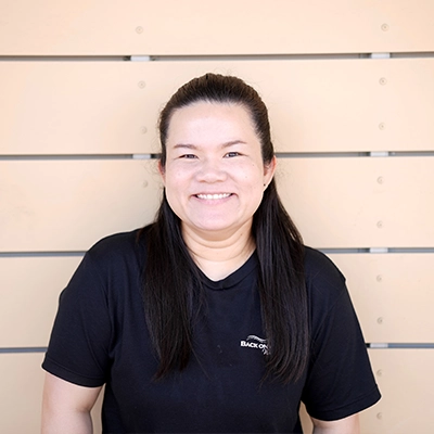 Massage Therapist Ava Oupala In Front Of Wooden Wall
